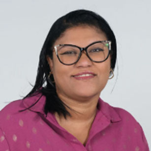 iuGO Digital - A woman with dark hair and glasses wearing a magenta blouse smiles in front of a plain, light background.